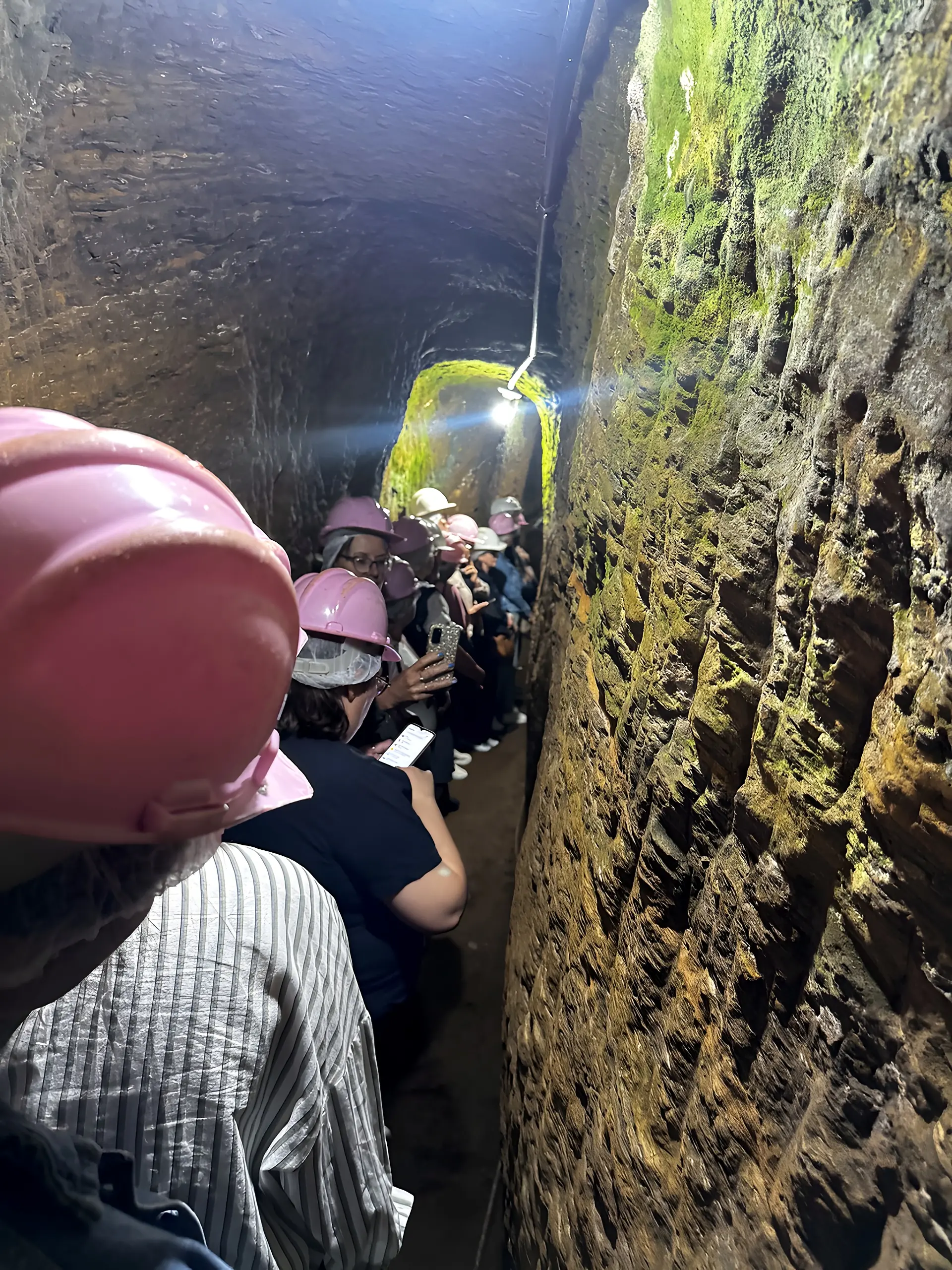Grupo de visitantes de capacete dentro do túnel da mina