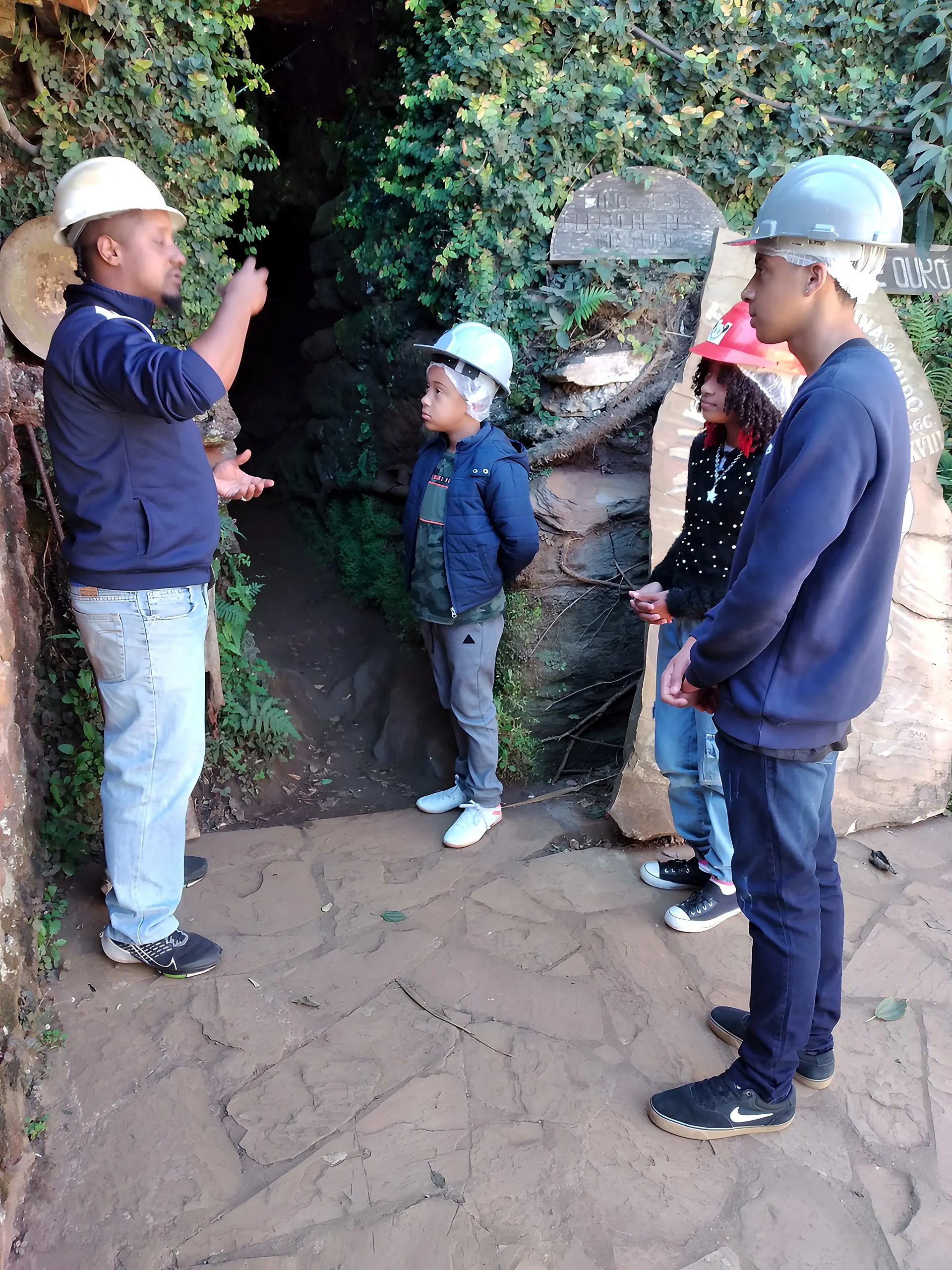 Guia explicando a história a visitantes de capacete na entrada da mina